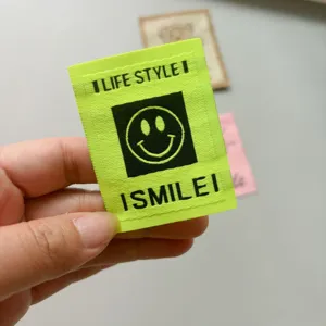 Etichetta tessuta smiley verde neon in dettaglio, perfetta per abbigliamento e borse DIY.