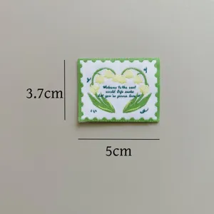 Detail view of embroidered lily of the valley woven patch, 3.7x5cm stamp design for DIY craft.