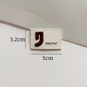 Close-up detail of a rectangular embroidered leather patch accessory designed for garments and bags.