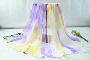 Detailed view of a gradient sheer chiffon scarf draped on a stand with floral props.