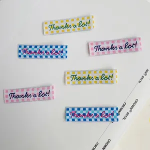 Colorful checkered woven fabric labels with cute embroidered text for clothing and crafts DIY.