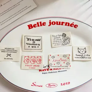 Gros plan de détails sur des étiquettes en tissu de coton avec motifs d'ours et de chats à coudre.