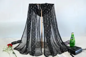 Detailed view of a black sheer sequin pleated scarf draped on stand with chic props.