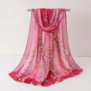 Détail de l'écharpe en mousseline à fleurs roses suspendue sur une barre montrant le beau motif.
