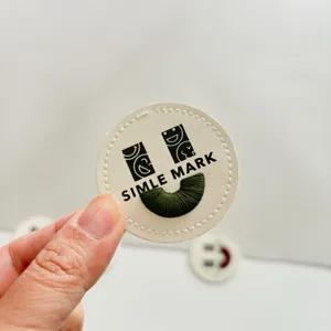 Round leather patch embroidered clothing badge detail view with smiley face and Letters.