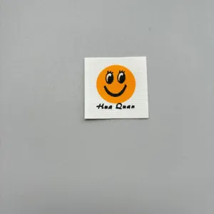 Close up of a DIY clothing woven cloth label featuring a cute smiling face and text detail.