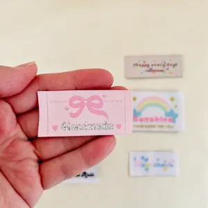 Gros plan d'étiquettes en tissu tissé mignonnes avec texte handmade pour vêtements DIY.