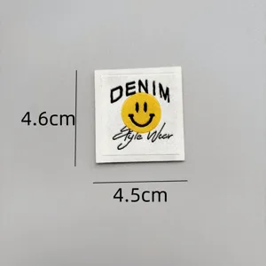 Close-up detail of a woven smiley face patch, embroidered denim style clothing accessory.