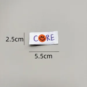 Detail view of the woven smiley face clothing label, showing embroidery and exact dimensions.