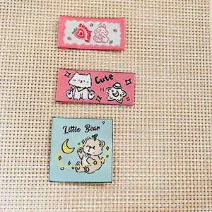 Detailed view of cute cartoon woven labels featuring bear, rabbit, and cat designs for DIY crafts.