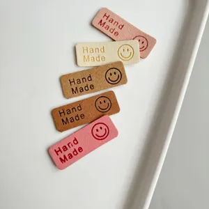 Detailed shot of colorful faux leather handmade labels with cute smiley face for DIY crafts.
