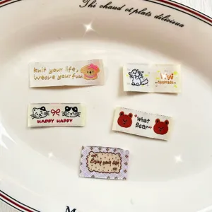 Primo piano di etichette tessute a tema cartone animato con ricami di animali per lavori manuali.