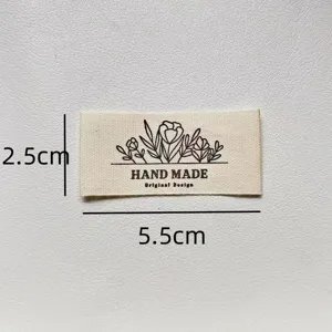 Close-up detail of minimalist handmade fabric label with floral design and dimensions.
