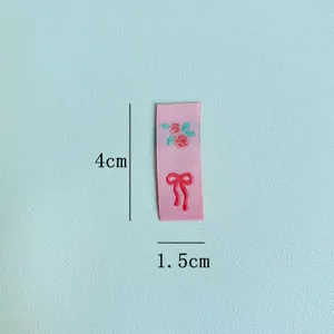 Etichetta tessuta rosa con ricamo di rose e fiocco per accessori di abbigliamento 4x1,5cm