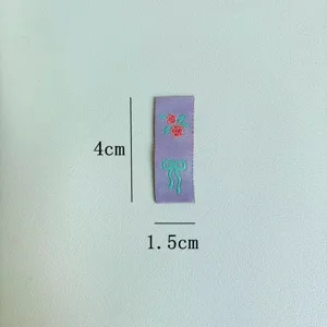 Primo piano dettaglio di una piccola etichetta tessuta viola con ricamo di rose e fiocco.