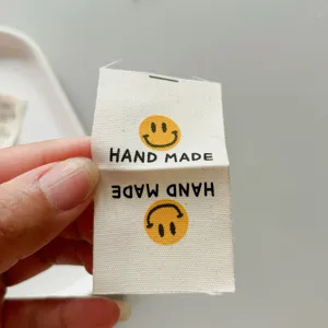 Cotton handmade woven label with cute smiley face for clothing, bags and socks accessories.