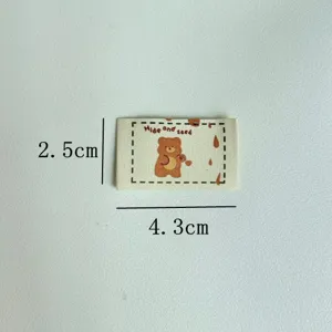 Detail shot of handmade cartoon bear woven clothing label, DIY sewing accessory fabric patch.