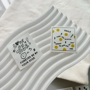 Custom woven clothing labels with cute smiley face patterns and English text for garments.