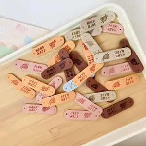 Close-up detail of colorful handmade leather labels with pre-punched holes and cute yarn ball patterns.