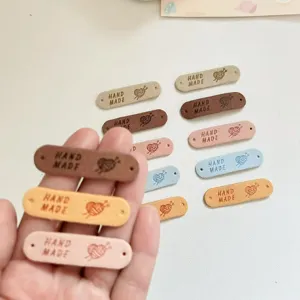Detailed view of colorful handmade leather labels with holes, heart yarn icon, DIY craft tags.