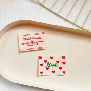Close-up detail of cotton decorative fabric labels with cute red hearts and French text print.