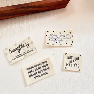 Detailed shot of cotton fabric sewing labels with inspiring English quotes and cute decorative patterns.