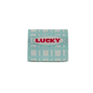 Blue and white plaid folded fabric label with red LUCKY embroidery for handmade bags and crafts.