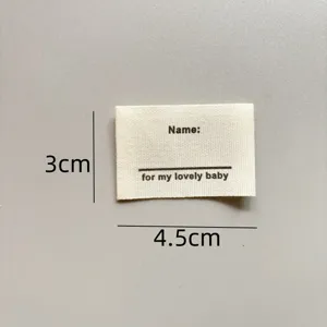 Detail view of a handmade cotton name label, 3x4.5cm fabric patch for DIY garment sewing.