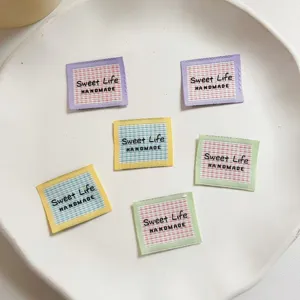 Detailed close-up view of handmade checkered fabric labels showcasing neat embroidery work.
