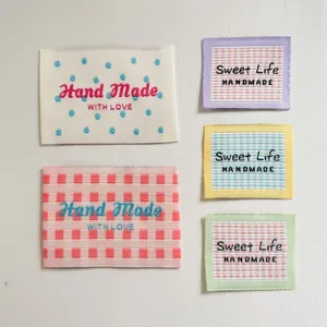 Woven fabric labels with cute plaid and polka dot embroidery designs, perfect for sewing crafts.