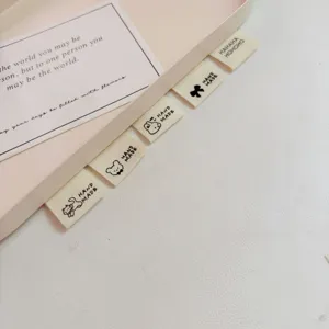 Detailed close-up of cute cartoon cotton fold labels for clothing, socks, and DIY handmade crafts.