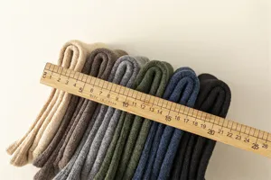 Detailed view of stacked woolen winter socks in various colors with measurement ruler.