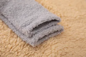 Gros plan sur la texture des chaussettes duveteuses en polaire corail grise pour l'hiver.