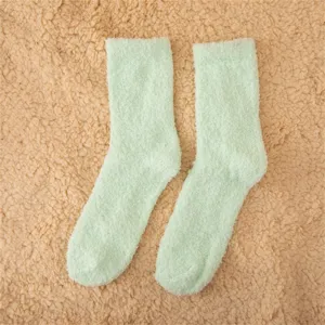 Gros plan détaillé de chaussettes de nuit pelucheuses en polaire douce vert pastel, douillet.