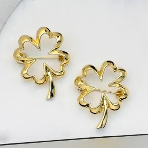 Gold hollow four-leaf clover brooch pin for women, stylish minimalist clothing accessory.