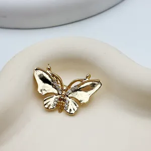 Close-up detail shot of a gold butterfly brooch with shimmering rhinestone crystal accents.
