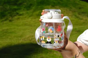 Bouteille d'eau en plastique transparent avec autocollants mignons et sangle pour l'extérieur.