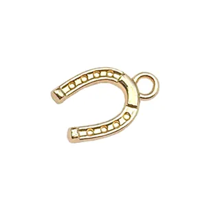 Golden horseshoe charm detail, DIY jewelry making pendant, metal alloy accessory close-up.