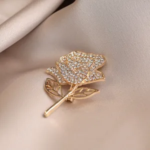 Close-up detail of a luxury crystal rose flower brooch with shining rhinestones and gold finish.