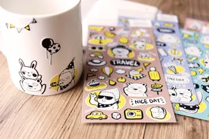 Primo piano dei dettagli di simpatici adesivi di cancelleria con animali cartoni animati e tazza.
