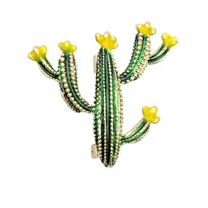 Close-up detail of cute cactus brooch, green enamel and yellow flower, shiny gold-tone metal.