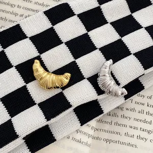 Detail shot of gold and silver croissant metal brooch set, stylish collar accessory for couples.