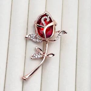 Exquisite rose brooch detail, featuring red crystal and sparkling rhinestones in rose gold.