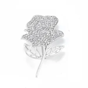 Detailed close-up of silver rhinestone rose brooch, sparkling crystal petals and cutout leaves.