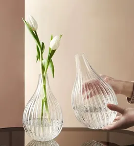 Transparent glass vase with ribbed design, elegant tear-drop shape for hydroponic floral decor.