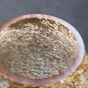 Detailed view of large glass vase with crackle texture and golden sparkle interior decor.