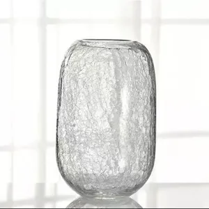 Detail view of large crackle glass vase for flowers, clear textured home decor accent.