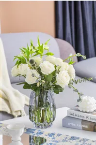 Modern vertical ribbed glass vase with white artificial roses for living room decor.