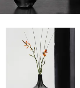 Detailaufnahme einer eleganten schwarzen Glasvase mit dekorativen orangefarbenen Blumen.