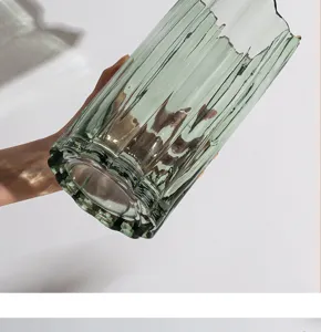 Close-up van een groene gestreepte glazen vaas met duidelijke verticale ribbels en textuur.